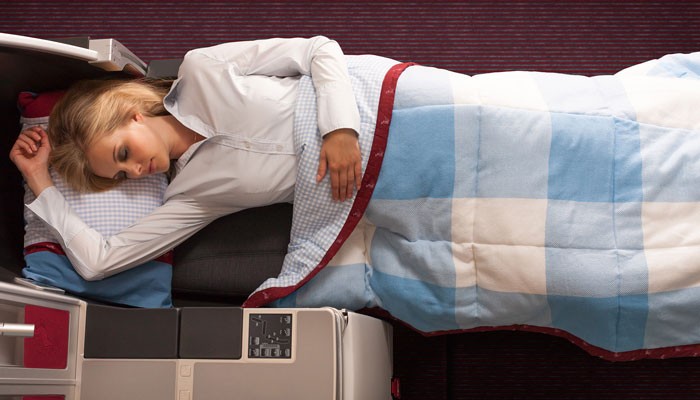Schlafende Frau auf Flatbed in Kabine der Austrian Airlines