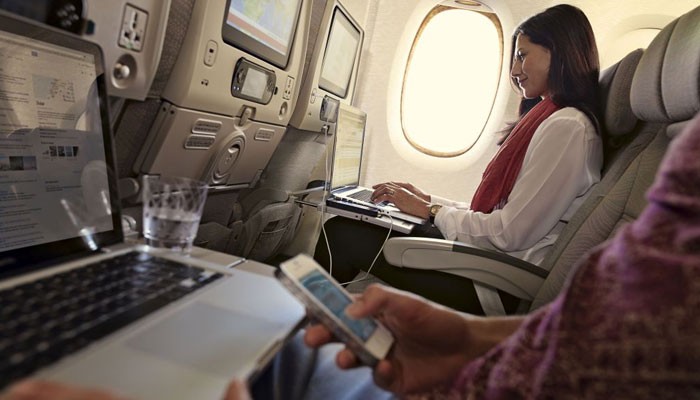 Passagiere mit Laptop und Smartphone in der Emirates-Kabine