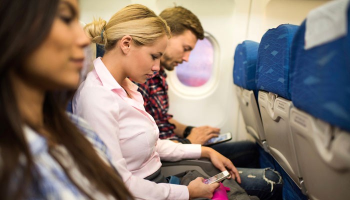 Drei Passagiere mit Smartphones in der Kabine