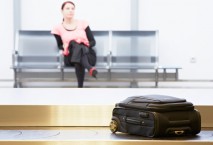 Frau wartet vor Gepäckband auf Koffer