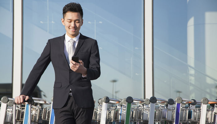 Asiate mit Handy im Flughafen
