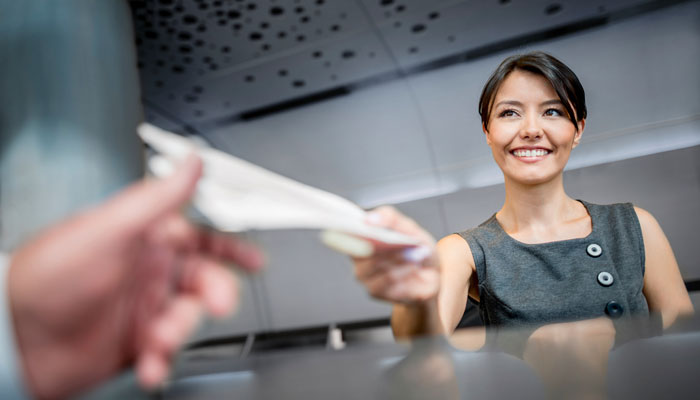 Dame hinter Airline-Schalter händigt Bordkarten aus