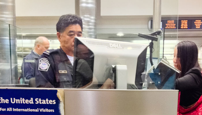 Frau steht am USA Border Control Schalter, Foto: iStock