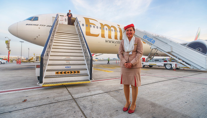 Emirates Stewardess vor einem Flugzeug
