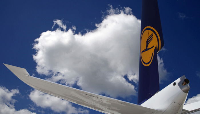 Flügel einer Lufthansa-Maschine vor leicht bewölktem Himmel