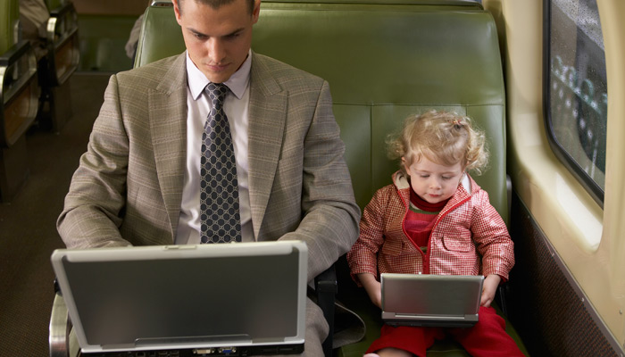 Vater und Tochter im Zug mit Laptop und DVD Player
