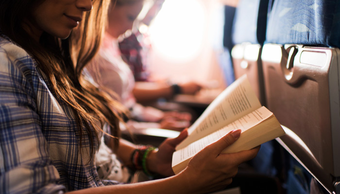 Frau liest ein Buch im Flugzeug