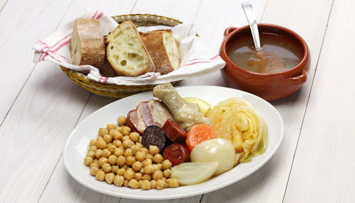 Spanisches Gericht mit Hühnchen, Kichererbsen und Suppe