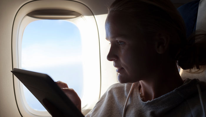 Frau surft auf Tablet im Flugzeug