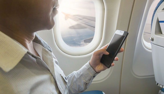 Mann mit Smartphone im Flugzeug
