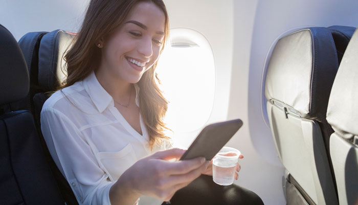 Frau mit Smartphone in Flugzeugkabine