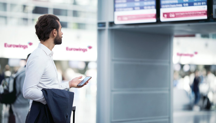 Mann vor Anzeigentafel mit Eurowings-Check-in-Schaltern im Hintergrund; Foto: Eurowings