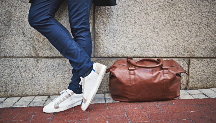 Junger Mann mit weißen Sneakers und Reisetasche; Foto: iStock.com/People Images
