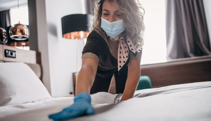 Young woman wearing protective face mask and gloves while working at a hotel