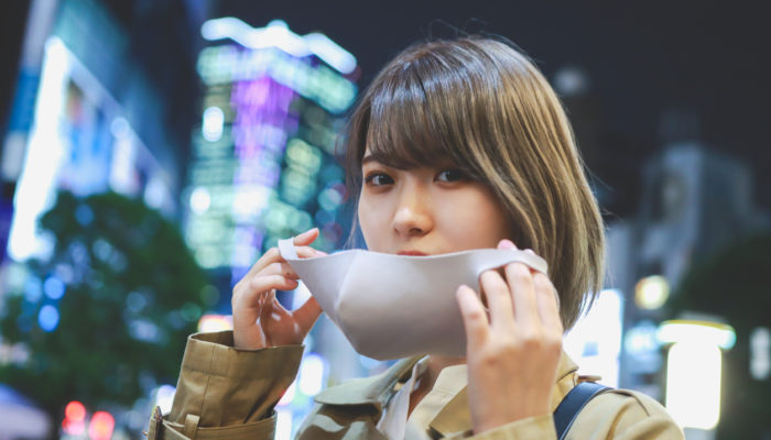 Japanerin setzt gerade ihre Maske auf. Foto kyonntra/iStock
