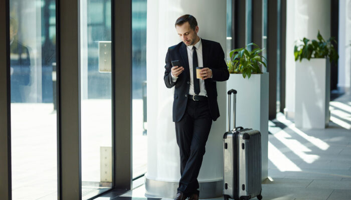 Geschäftsmann Warten Kaffeebecher to goiting for flight with his trolley suitcase in airport